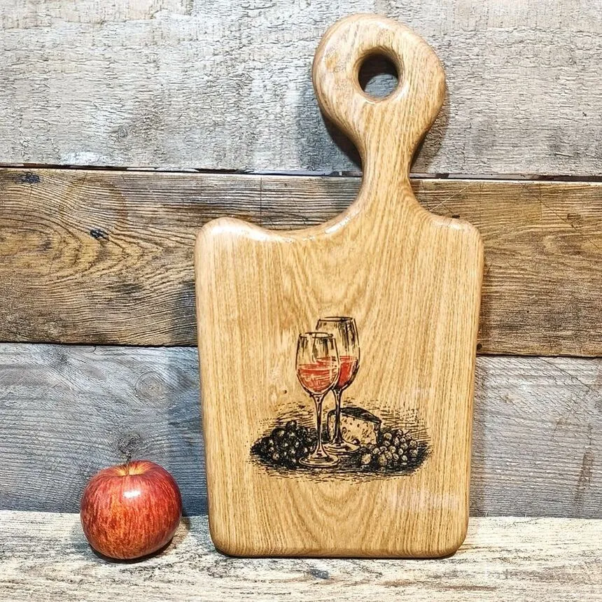Grawerowana deska z drewna oliwnego Nela Wood z motywem wina, gotowa do serwowania wykwintnych przekąsek.