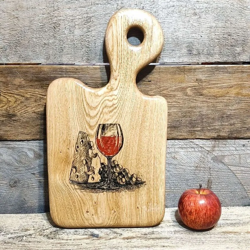 Grawerowana deska dębowa Nela Wood z motywem wina, serami i winogronami podczas wieczornej degustacji.
